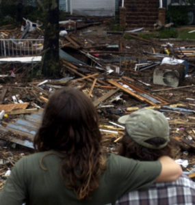 Two people looking onto debree created by a natural disaster.