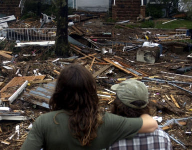 Two people looking onto debree created by a natural disaster.